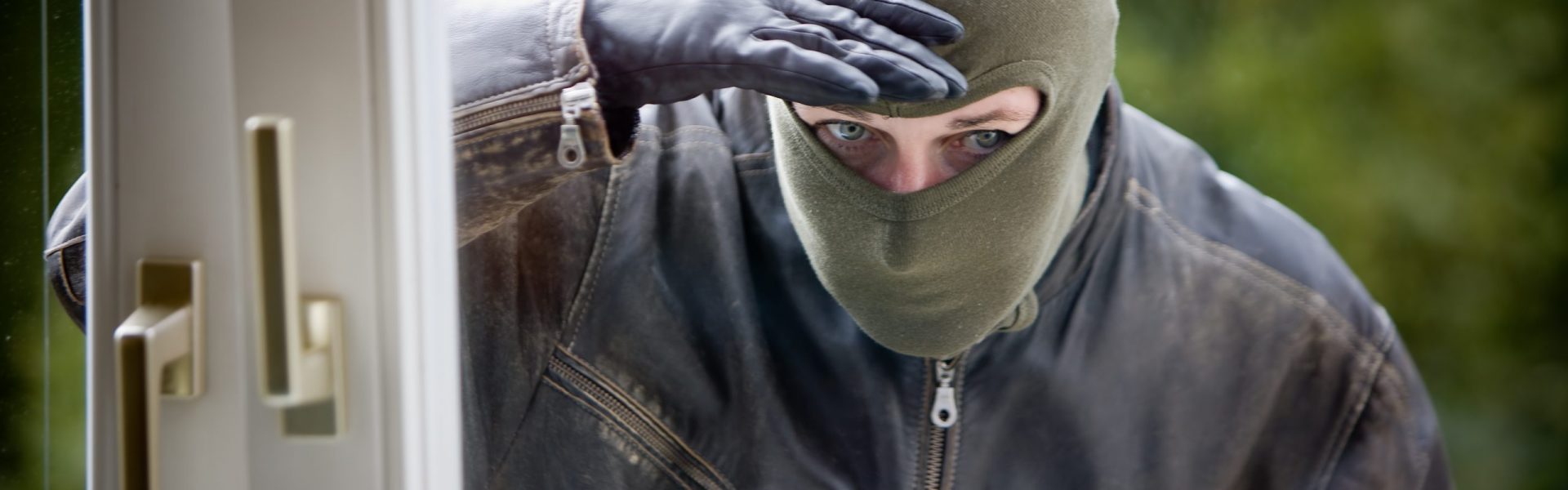 Cambrioleur qui inspecte l'intérieur d'une maison avec un pied de biche et une lampe torche